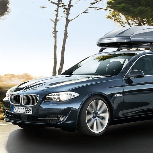 Beispielbild für Dachboxverleih. Ein fahrender BMW mit Dachbox auf dem Autodach.