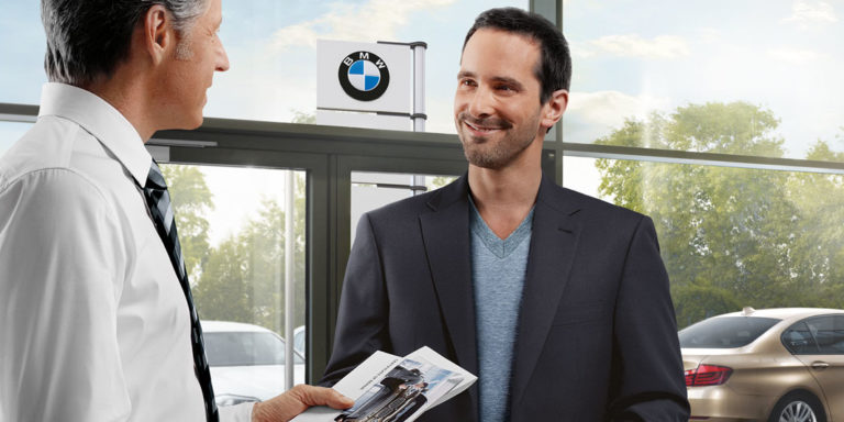 Beispielbild für Hol- und Bringservice. Zwei Männer sind in der Einganglobby von einem BMW Händler.