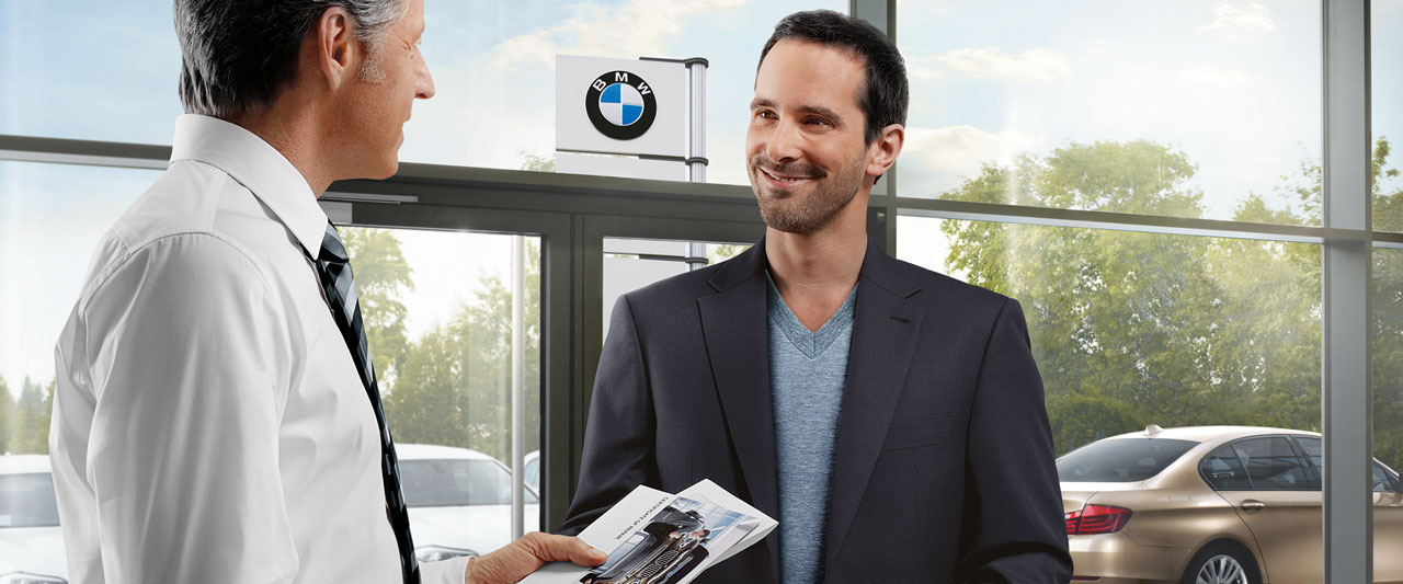 Beispielbild für Hol- und Bringservice. Zwei Männer sind in der Einganglobby von einem BMW Händler.