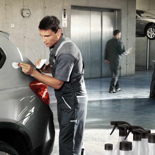 Service Lackreparatur. Ein Mechatroniker korrigiert einen Kratzer/Lackschaden an einem BMW in einer Werkstatt.