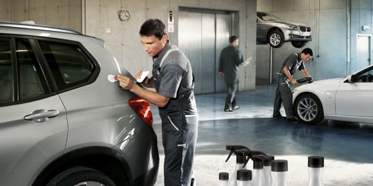 Service Lackreparatur. Ein Mechatroniker korrigiert einen Kratzer/Lackschaden an einem BMW in einer Werkstatt.