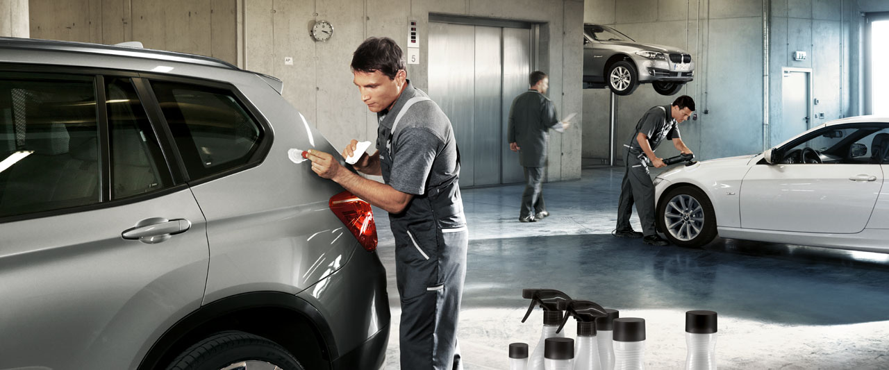 Service Lackreparatur. Ein Mechatroniker korrigiert einen Kratzer/Lackschaden an einem BMW in einer Werkstatt.