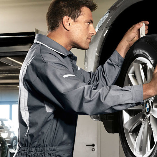 Mechatroniker wechselt Reifen eines Fahrzeugs. Beispielbild für Räder- und Reifenservice.