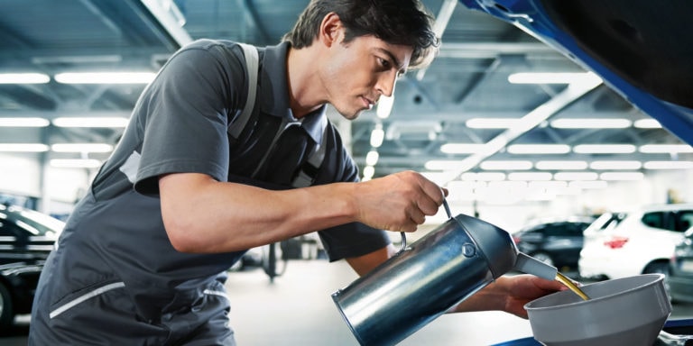 Beispielbild für Service Saisoncheck. Mechatroniker füllt Motoröl in Motor eines Fahrzeugs.