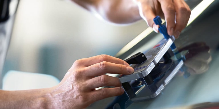 Das Bild zeigt eine Scheibenreparatur von einem Mechatroniker an der Frontscheibe eines Fahrzeugs.