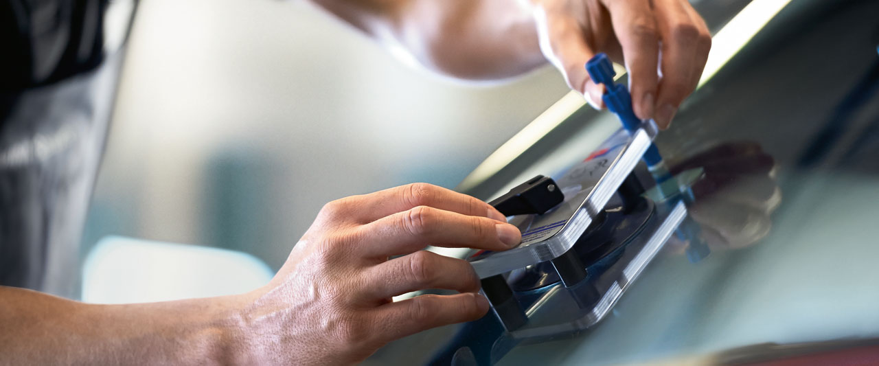 Das Bild zeigt eine Scheibenreparatur von einem Mechatroniker an der Frontscheibe eines Fahrzeugs.