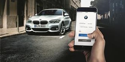 Beispielbild für Online-Terminvereinbarung. Auf dem Bild ist ein BMW und ein Smartphone mit der BMW App zu sehen, welche bedient wird.